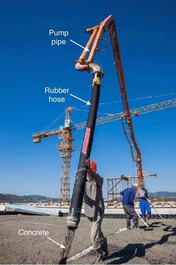 Concrete pump pipe connected to a rubber hose placing concrete on a construction site